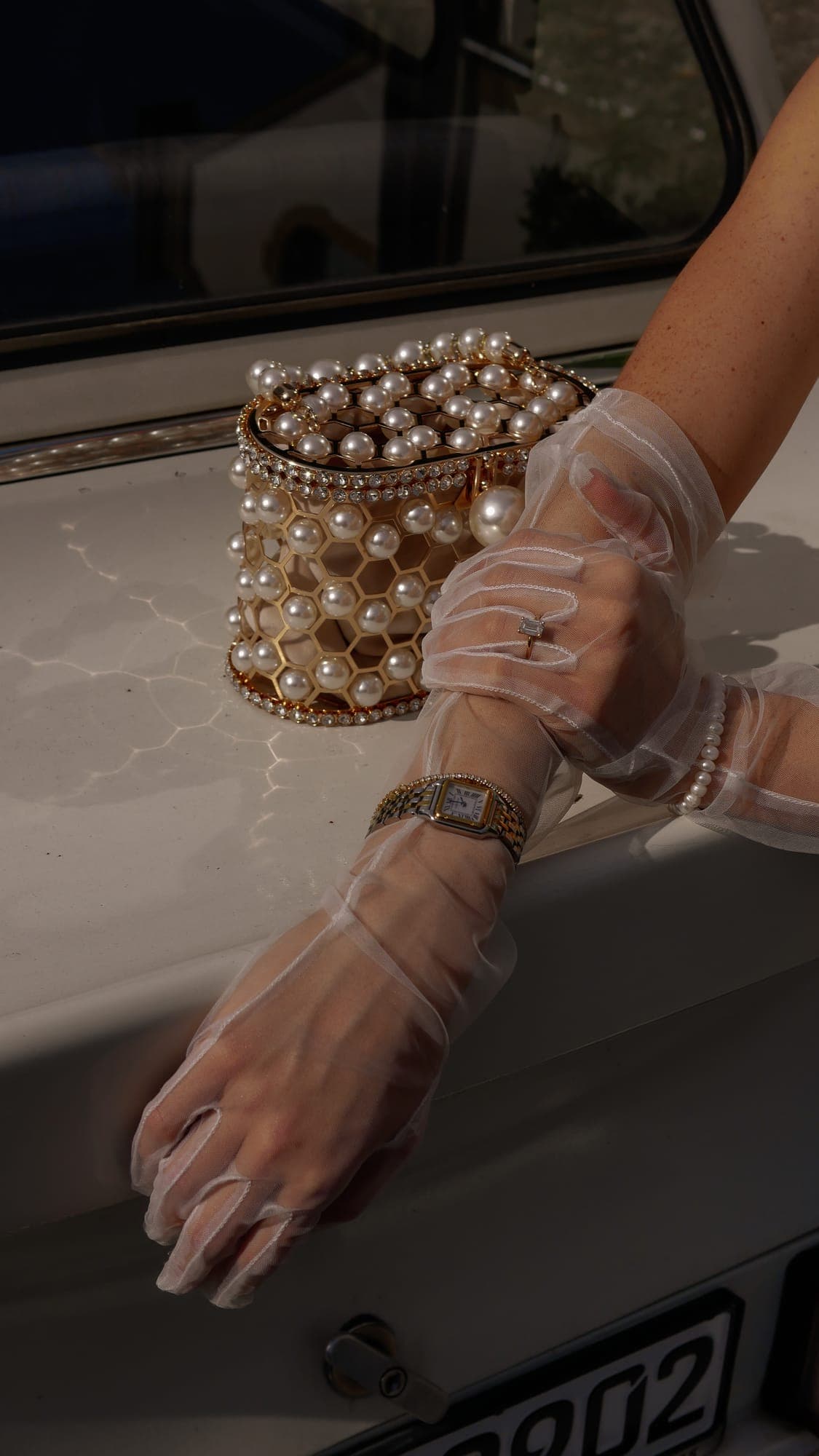 Detail: Hand mit Tüllhandschuh und Perlentasche am Auto