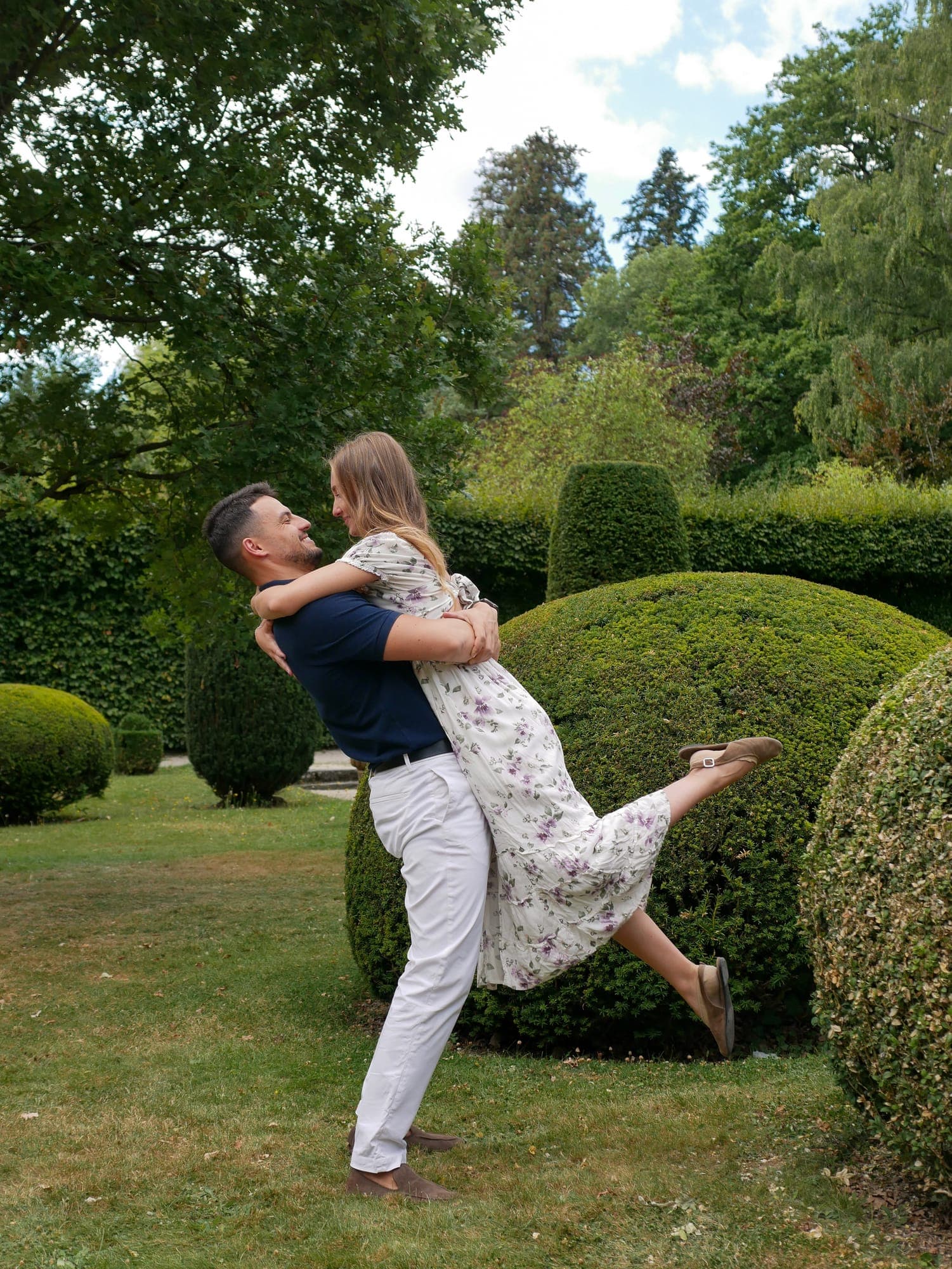 Er hebt sie im Schlossgarten hoch, sie streckt lachend ein Bein aus