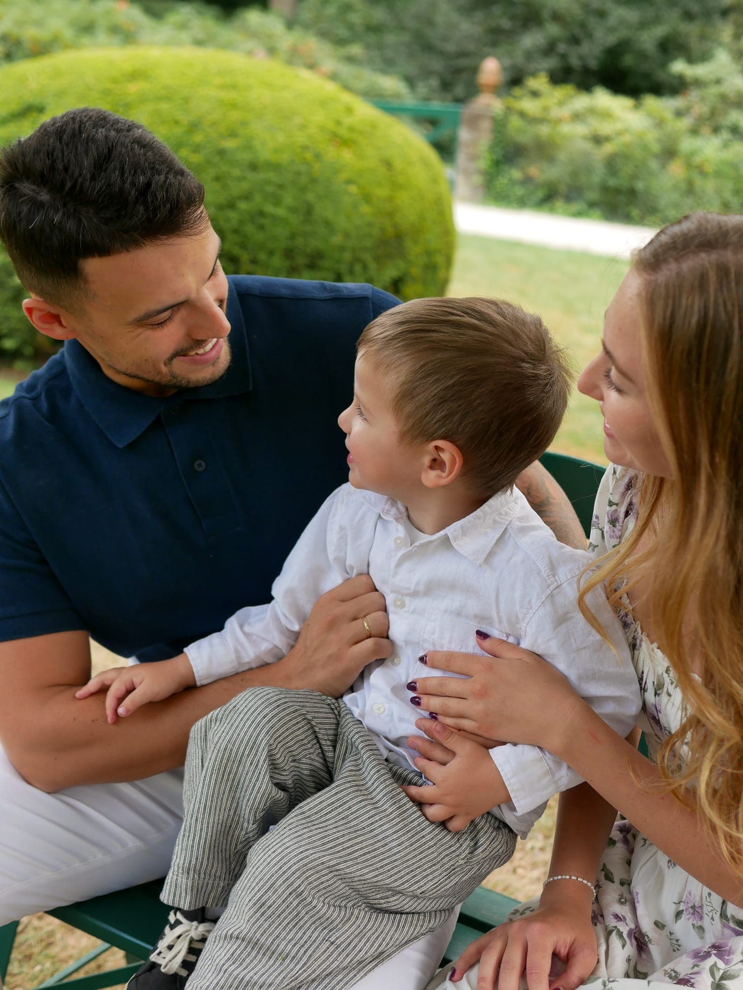 Familie lacht gemeinsam mit ihrem kleinen Sohn im Garten